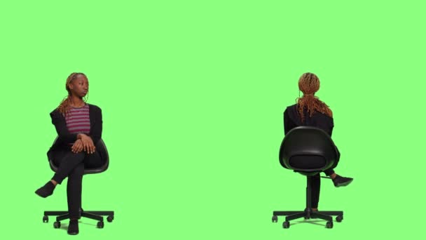 Das weibliche Model sitzt auf einem Stuhl in zwei Seiten der Greenscreen-Kulisse, wartet und bereitet sich im Studio vor. Ungeduldige Frau sitzt auf einem Hocker und wartet auf die Vorbereitung, grüner Hintergrund. - Filmmaterial, Video