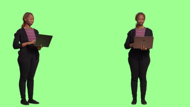 Сучасна жіноча модель, що тримає ноутбук та переглядає Інтернет, використовує портативний ПК для прокрутки через веб-сайт. Усміхнена молода дівчина стоїть над повноцінним зеленим екраном, соціальні медіа
. - Кадри, відео