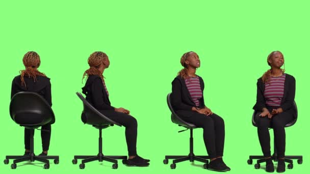 Lächelnder junger Mensch auf Stuhl, der in Greenscreen-Hintergrund sitzt, Ganzkörper-Greenscreen-Hintergrund. Lässige Erwachsene warten und bereiten auf vier Seiten, warten und sitzen Vorbereitungen im Studio. - Filmmaterial, Video