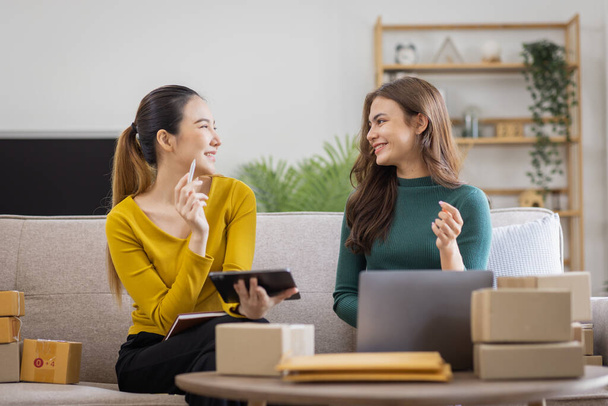 Two Asian women to Startup small business SME entrepreneur of freelance working on laptop computer with parcel box on table laptop at home, online marketing packaging and delivery SME idea concept - Photo, Image