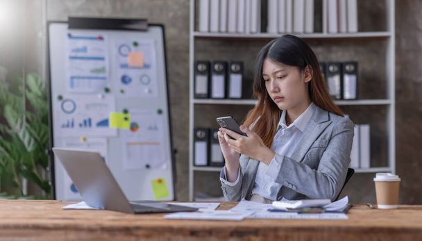 Mladé podniky Asijské ženy jsou ve stresu při práci na notebooku telefon Unavená asijská podnikatelka s bolestí hlavy v kanceláři, pocit smutku nebo nevolnosti na pracovišti kopírovat prostor na pracovišti kancelář. - Fotografie, Obrázek