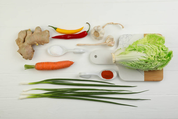 Flat lay composition with fresh Chinese cabbages and ingredients on white wooden table - Foto, imagen