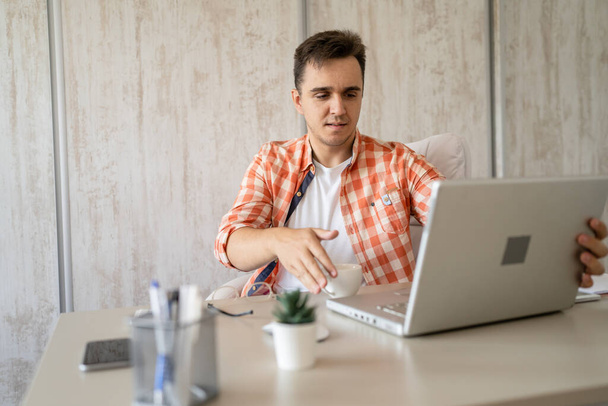 One caucasian man sitting at office at work working on laptop computer in day young freelance or entrepreneur businessman online business copy space young adult finishing or beginning confident think - Foto, Imagem
