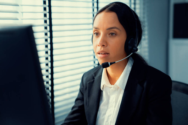 Competent female operator working on computer and talking with clients. Concept relevant to both call centers and customer service offices. - Photo, image