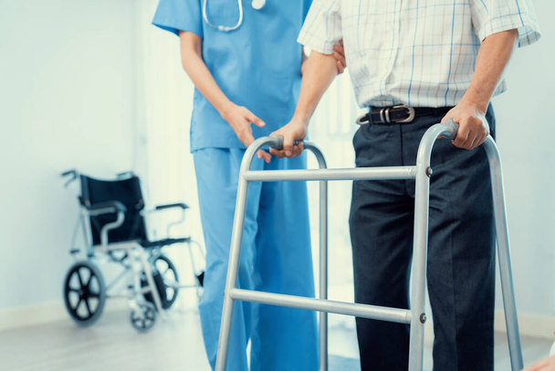 Physiotherapist assists contented senior man on folding walker. Recuperation for elderly, seniors care, nursing home. - Fotó, kép