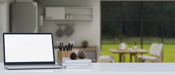 Laptop beyaz ekran modeli, kitap, kalem, çam kozalakları ve montaj için kopya alanı arka plandaki bulanık mutfağın üzerindeki beyaz masa üstünde ürününüzün görüntüsü. Görüntüyü yaklaştır. 3d görüntüleme, 3d illüstrasyon - Fotoğraf, Görsel