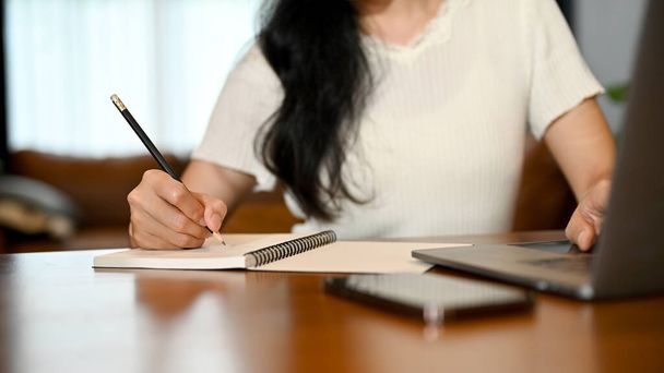 Une femme pigiste écrit son horaire de travail sur son carnet de rendez-vous personnel. image recadrée - Photo, image