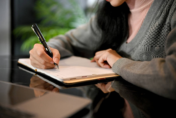 Красивая женщина что-то пишет в своем дневнике. Студентка колледжа делает домашнее задание. обрезанный и крупный план - Фото, изображение