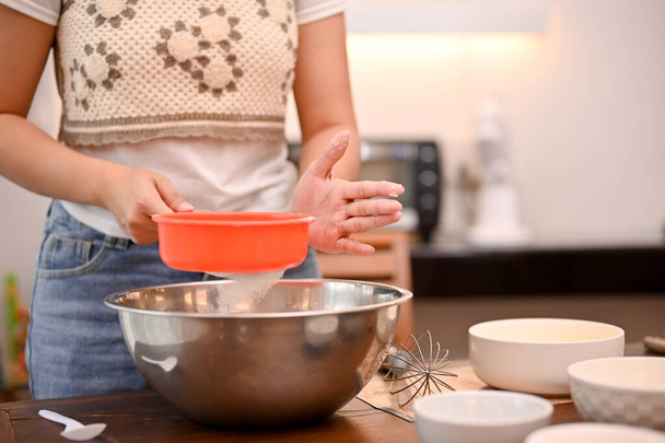 Samice peče ve své kuchyni dortíky a připravuje si domácí mouku s moučným sítem. cupcake recept koncept - Fotografie, Obrázek