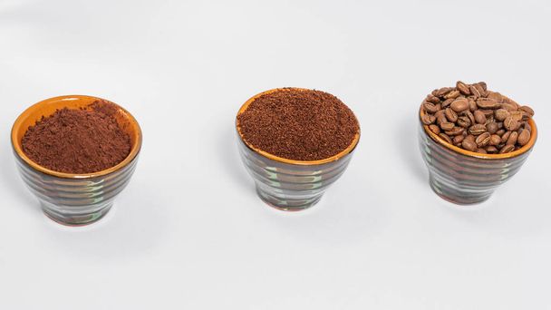 Tři šálky s kávovými zrny, mletá káva a kakao pro srovnání, káva energetický nápoj, bílé pozadí a hrnky s různými kávami. - Fotografie, Obrázek