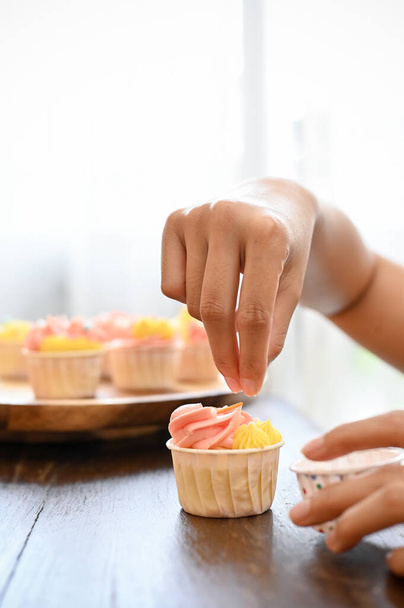 lähikuva, ammatillinen naispuolinen leipuri tekee cupcake talossaan, koristelu hänen tuoretta cupcake strösseleitä. - Valokuva, kuva
