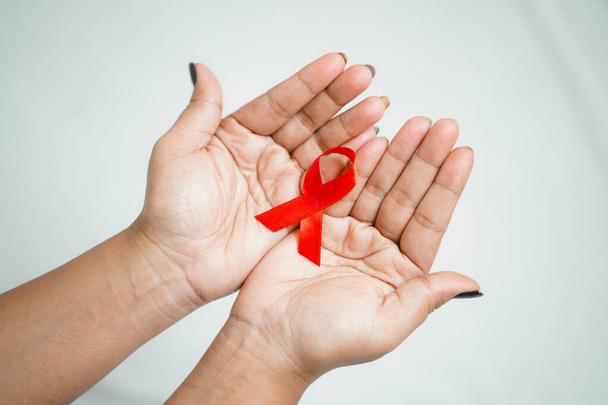 Worlds HIV Aids Day 2022-2023, Closeup hands holding red aids awareness ribbon on white background concept of world aids day HIV - 写真・画像