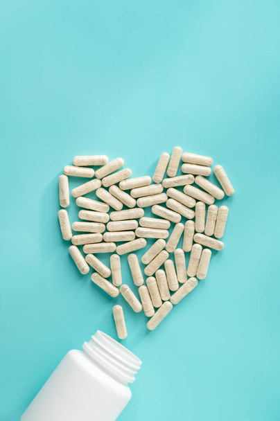 White pill bottles on blue background. Heart desease, treatment concept. Food supplements, vitamins and medicaments. - Foto, imagen