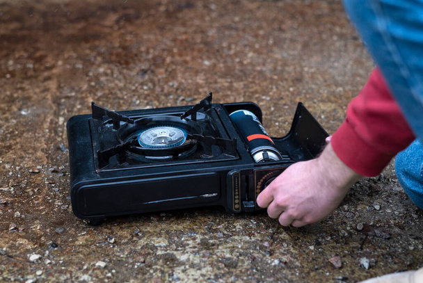 Active lifestyle. A man's hand turns on a portable gas stove. An alternative source for cooking at home during a power outage - Foto, immagini