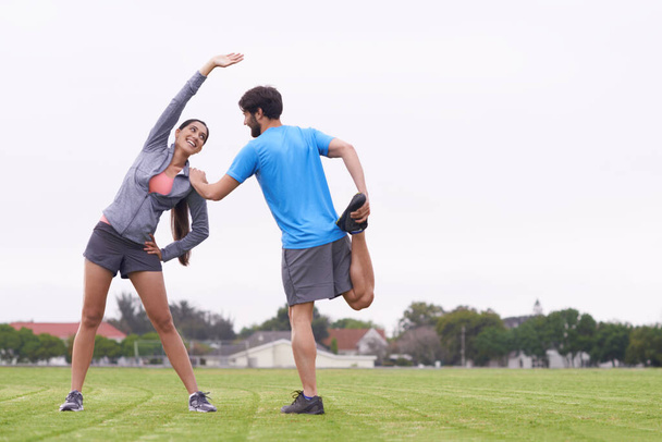 My best workout partner. two people helping each other stretch on a grassy field - Foto, Imagen