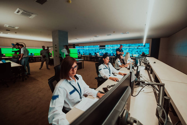 group of female security operators working in a data system control room Technical Operators Working at the workstation with multiple displays, security guards working on multiple monitors in - Foto, Imagem