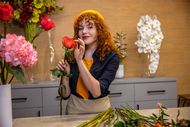 Flower shop. Young ginger girl in beret in a flower shop - Photo, Image