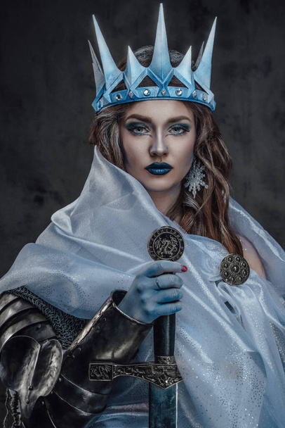 Retrato de reina de hielo con corona y espada de piel fría. - Foto, Imagen