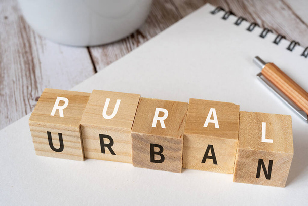 "RURAL" ve "URBAN" yazılı tahta bloklar kavram metni, bir kalem, bir defter ve bir fincan. - Fotoğraf, Görsel