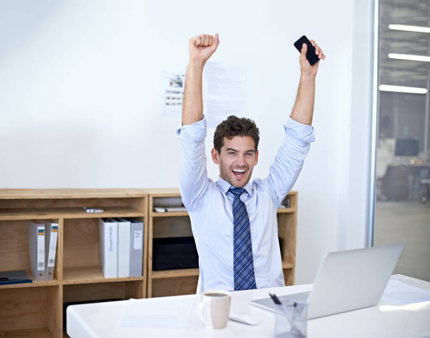 I got the deal. A young businessman celebrating something while seated behind his desk - Photo, image