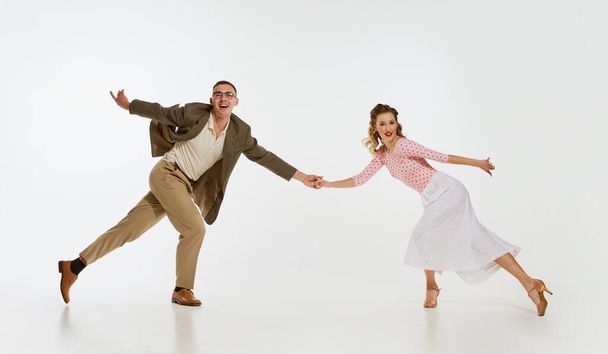 Two emotional dancers in vintage style clothes dancing swing dance, rock-and-roll isolated on white background. Timeless traditions, 1960s american fashion style and art. Couple look happy, delighted - Fotoğraf, Görsel