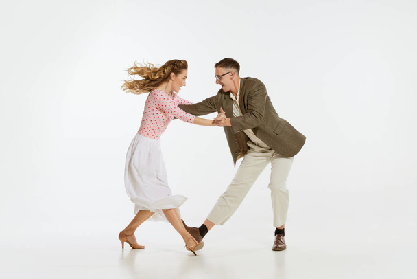 Two emotional dancers in vintage style clothes dancing swing dance, rock-and-roll isolated on white background. Timeless traditions, 1960s american fashion style and art. Couple look happy, delighted - Foto, immagini
