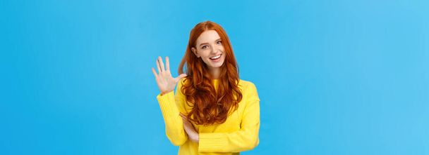 Cheerful, charismatic friendly redhead female showing high five, number fifth as making order, reservation or booking place for party, counting, standing blue background carefree in yellow sweater. - Photo, Image