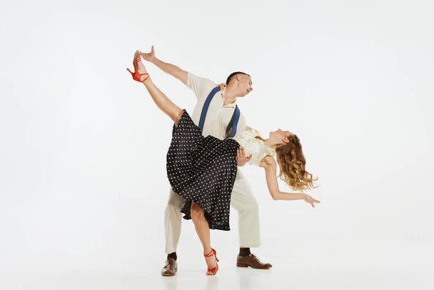 Dynamic portrait of happy, stylish and energetic dancers dancing lindy hop or swing dance isolated on white background. Concept of music, energy, happiness, mood, action, style - Фото, изображение