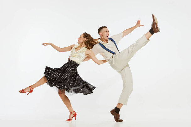 Love in motion. Young excited man and woman wearing 60s american fashion style clothes dancing retro dance isolated on white background. Music, energy, happiness, mood, action - Fotografie, Obrázek