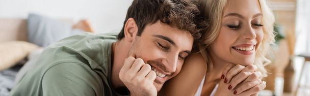 Χαρούμενο ζευγάρι στην πιτζάμα ξαπλωμένο στο κρεβάτι το πρωί, πανό  - Φωτογραφία, εικόνα