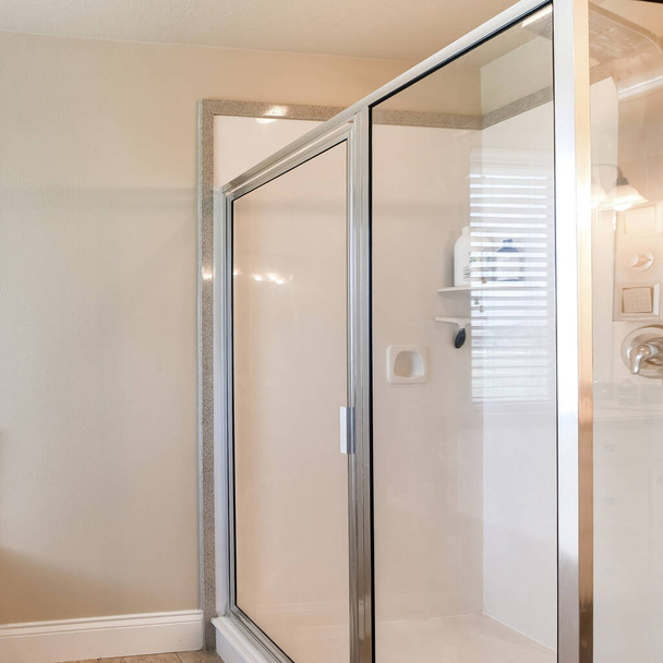 Négyzet Fürdőszoba belső sarok káddal és zuhanyfülke üveg és alumínium keret. Van egy fedélzet szerelt csaptelep a kád közelében az ablakok a bal oldalon, és állvány zuhanyzó panel a jobb oldalon. - Fotó, kép
