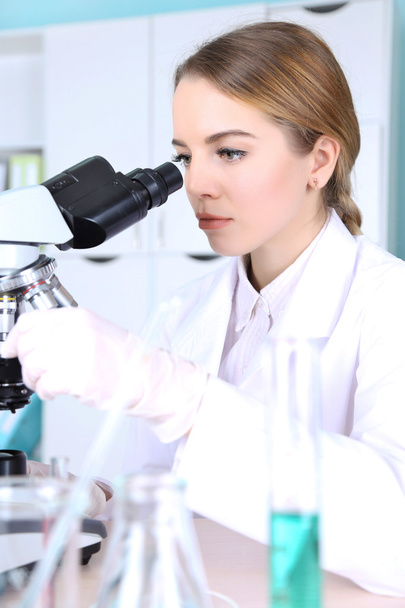 Young female scientist with microscope in laboratory - Fotoğraf, Görsel