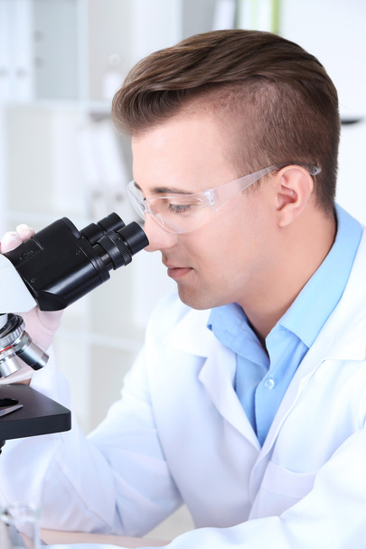 Científico masculino usando microscopio en laboratorio
 - Foto, Imagen