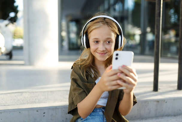 Teen smiling girl making selfie on summer day or having mobile conversation on smartphone,portrait. - Photo, Image
