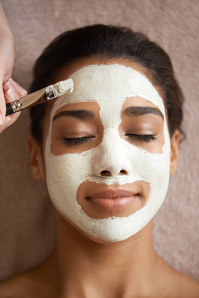 Tratándose a sí misma con una máscara facial de lujo. una joven que recibe un tratamiento facial en un spa - Foto, Imagen
