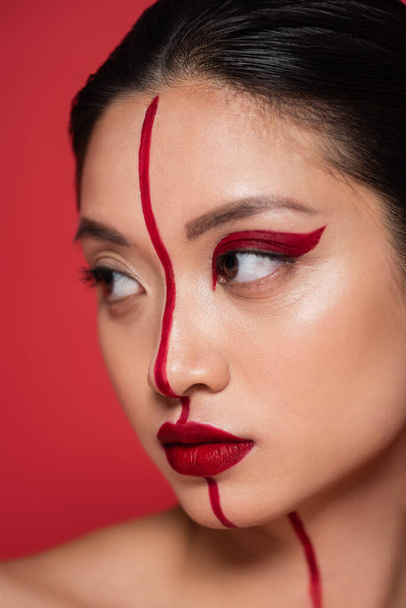 close up portrait of pretty asian woman with creative visage on face divided with line isolated on red - Fotografie, Obrázek