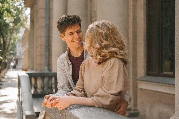Jongeman en vrouw die naar elkaar kijken zijn op een date buiten op straat op een zonnige dag.. - Foto, afbeelding
