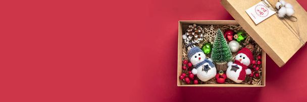 Ręcznie robiony pakiet pielęgnacyjny, sezonowe pudełko z zabawkami, wystrój świąteczny na czerwonym stole Spersonalizowany ekologiczny kosz dla rodzin, przyjaciół, dziewczyny na 24 grudnia, Boże Narodzenie, Nowy Rok Flat lay. - Zdjęcie, obraz