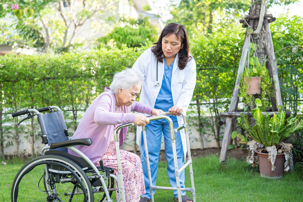 Врач помощь и уход азиатских пожилых или пожилых пожилая женщина пациентка, сидящая на инвалидной коляске в парке в палате медсестринской больницы, здоровый сильный медицинский концепт. - Фото, изображение