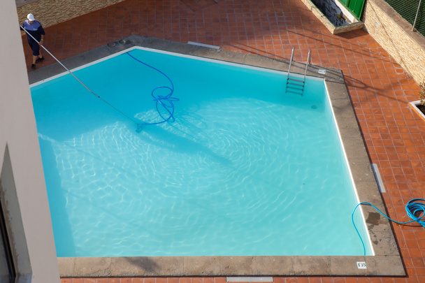 Man cleaning the swimming pool with vacuum equipment. swimming pool cleaning. a man is cleaning the pool. service care. - Photo, Image