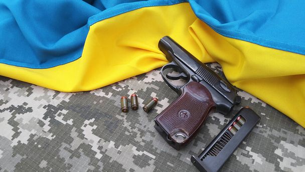 A Makarov pistol with cartridges against the background of a military camouflage pixel and the flag of Ukraine. PM is shorter. War in Ukraine. - Foto, imagen