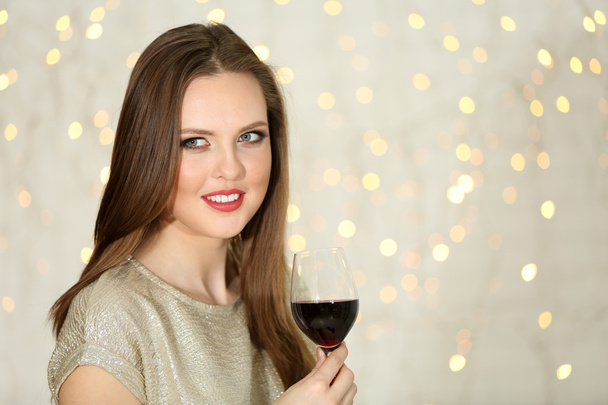 Smiling girl with glass of wine on lights background - Фото, зображення