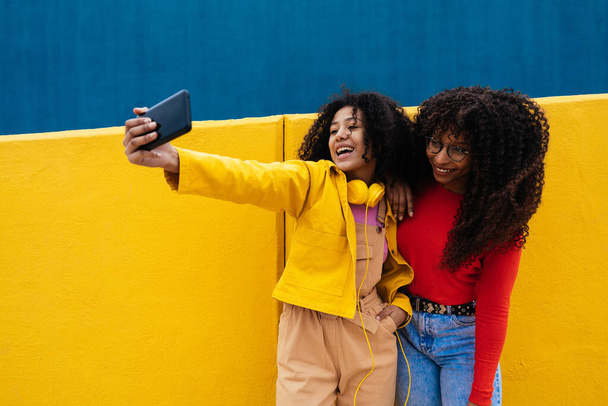 Young happy women taking selfies with the smartphone. Teenagers having fun outdoor after school - Foto, Imagem