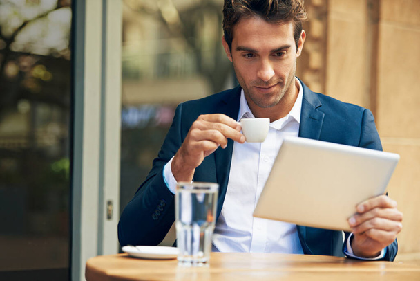 Beszámolok a netes hírekről munka előtt. Egy fiatal üzletember használja a digitális táblagépét, miközben kávézik egy szabadtéri kávézóban. - Fotó, kép