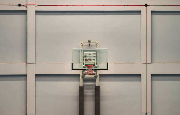 Bangkok, Thailand - Oct 15, 2020 : View of Basketball fiberglass backboard, Hoop orange metal ring and white  orange net with cement wall background in the gym. Empty basketball basket, Space for text, Selective focus. - Foto, Imagen