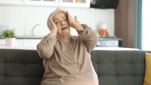 Problemas de salud de anciana triste. Mujer mayor que sufre de ataque de pánico o concepto de pérdida de memoria con fuerte dolor de cabeza. - Foto, imagen