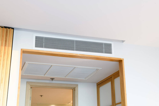Acondicionador de aire por conducto para casa u oficina. Acondicionador de aire tipo casete montado en el techo y luz moderna de la lámpara en el techo blanco. - Foto, Imagen