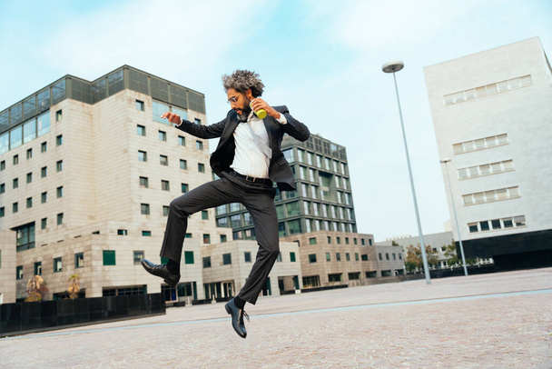 Young entrepreneur jumping and dancing to celebrate his successful day at work. Concept about freedom and carefree in business career - Foto, Bild