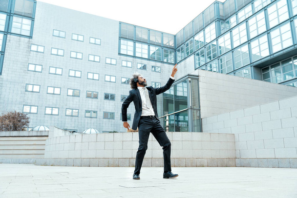Young entrepreneur business man listening to music and dancing outside the office. Concept about freedom and success in business - Fotoğraf, Görsel