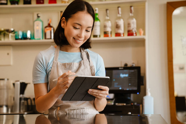 Young asian waitress woman working with tablet computer in cafe - Фото, зображення